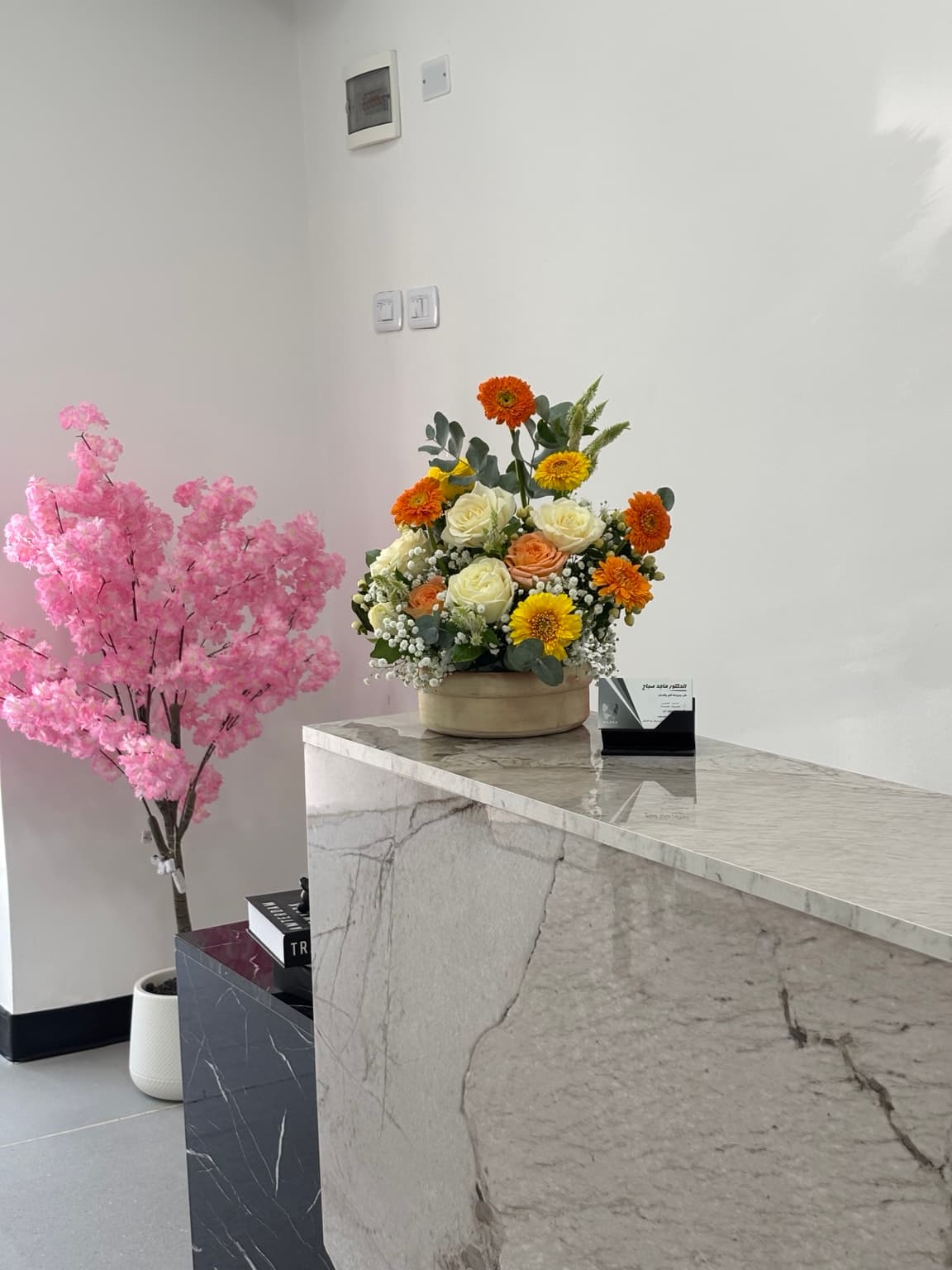 Marble reception desk with a flower bowl and business cards showing Dr. Majed Sabbah’s name