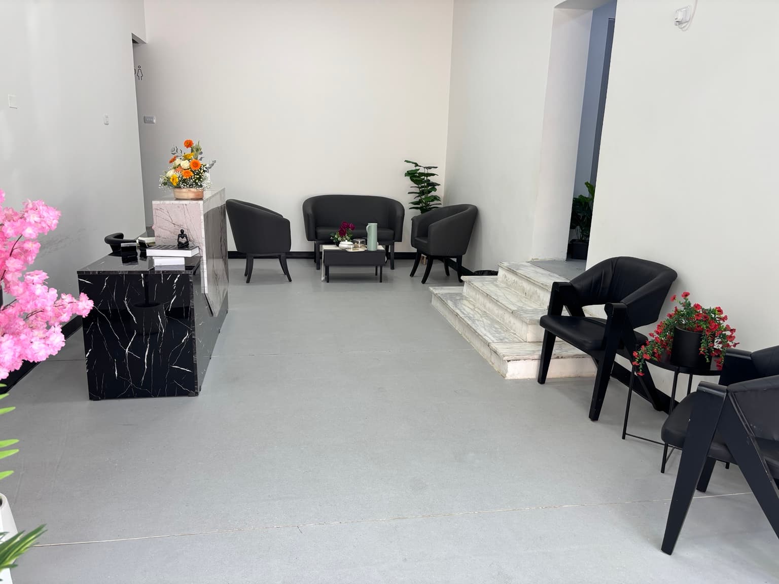 Clinic reception and waiting area: a marble desk, dark seating, and indoor plants Clinic reception and waiting area: a marble desk, dark seating, and indoor plants